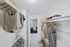 Carpeted walk in closet with clothes