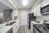 Modern kitchen featuring vinyl flooring, stainless-steel appliances, and a white quartz countertop.