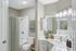 Bathroom with white counters, large mirror, vanity lighting, and white cabinetry