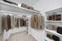 Carpeted walk in closet with clothes and built-in shelves