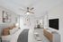 Carpeted bedroom with ceiling fan and TV