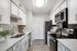 Modern kitchen featuring vinyl flooring, stainless-steel appliances, and a white quartz countertop.