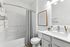 Bathroom with quartz counters, large mirror, vanity lighting, and white cabinetry