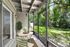 Charming screened patio with elegant white bistro set overlooking lush green garden, perfect for relaxation.