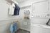 Modern laundry room with stacked washer and dryer, organized shelving, and hanging space. Efficient and tidy.