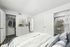 Bright bedroom featuring sleek hardwood flooring, a white dresser, and a convenient in-unit laundry space. Ample closet storage with modern decor accents.