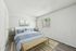 Bright and cozy bedroom with a stylish modern design, featuring a plush bed, elegant artwork, and natural light streaming through the window.