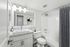 Elegant bathroom featuring a modern white vanity, sleek marble countertop, and stylish lighting. Includes a bathtub with a chic striped curtain and polished fixtures, all in a bright, airy setting.