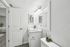 Elegant bathroom with a chic marble-topped sink, large mirror, and stylish lighting, offering modern comfort and freshness.