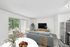 Bright and inviting living space showcasing a modern open-concept layout with a sleek kitchen and cozy sitting area, accented by a lush garden view.
