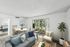 Bright and inviting living room with modern decor, cozy seating, and a view of the lush garden through large glass doors.