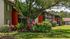 Charming apartment exterior with vibrant gardens, lush greenery, and inviting balconies in a serene setting.