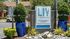 Inviting entrance to LIV at Winter Park Apartment Homes, featuring lush greenery and stylish blue planters in a serene setting.