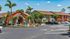 Charming apartment complex with vibrant landscaping, palm trees, and convenient parking under a clear blue sky.