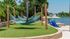Tranquil waterfront oasis with inviting blue hammocks and Adirondack chairs under striped umbrellas, perfect for relaxation.