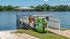 Charming lakeside dock with kayaks and paddleboards under a clear blue sky, perfect for water adventures and relaxation.