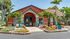 Inviting apartment entrance with vibrant landscaping, tropical greenery, and elegant blue planters.