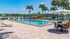 Inviting poolside oasis with elegant lounge chairs and palm trees, perfectly complemented by a serene lake view.