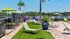 Charming outdoor patio with scenic lake views, featuring lounging chairs, vibrant green umbrellas, and lush palm trees, perfect for relaxation and entertaining.