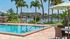 Luxurious poolside retreat featuring a sparkling blue swimming pool, lush landscaping, and serene lake views under sunny skies.
