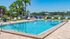 Luxurious outdoor swimming pool surrounded by lush greenery and stylish lounge chairs, offering a serene lakeside view.