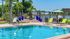 Luxurious outdoor pool area with elegant lounge chairs, vibrant blue planters, and tranquil lakeside views, perfect for relaxation and leisure.