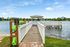 Inviting lakeside view featuring a charming wooden gazebo at the end of a scenic boardwalk, perfect for relaxation and enjoying serene waterside moments.