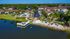 Idyllic waterfront apartment complex with lush greenery, a sparkling pool, and a charming dock extending into the tranquil lake.