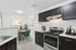 Modern kitchen with sleek dark cabinetry, stainless steel appliances, and elegant dining area featuring teal chairs and contemporary artwork.