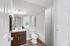 Bright and modern bathroom featuring elegant lighting, a sleek vanity, and stylish hardwood flooring.