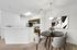 Chic open-plan dining area with elegant round table and modern kitchen featuring sleek cabinetry and contemporary lighting.
