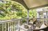 Inviting apartment balcony with cozy wicker chairs and lush green views, perfect for relaxation.