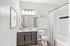 Bright and modern bathroom with sleek dark wood vanity, elegant wall art, and a pristine bathtub, creating a stylish and relaxing space.