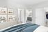 Chic bedroom with elegant decor, featuring a cozy bed, stylish dresser with art pieces, and an inviting bathroom entrance.