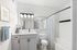 Bright and modern bathroom with elegant vanity, large mirror, and stylish shower curtain.
