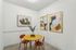 Chic dining nook with a modern yellow table, vibrant artwork, and stylish chairs, offering a cozy yet contemporary atmosphere.