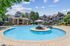 Swimming pool with sunbathing area, elegant architecture, and lush greenery under a clear blue sky.