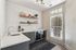 Clubhouse kitchen with sleek gray cabinets, elegant floating shelves, and a large window showcasing serene outdoor views.