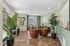 Clubhouse with modern decor, featuring sleek leather chairs, vibrant artwork, and lush green plants against soft pastel walls.