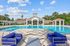 Swimminng pool area featuring stylish outdoor seating, large swimming pool, and elegant clubhouse under a bright blue sky.