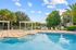 Swimming pool area with stylish pergolas, lush greenery, and comfortable lounge chairs, perfect for relaxation and leisure.