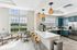 Clubhouse kitchen with blue cabinets, modern appliances, and large windows showcasing an inviting outdoor view. Stylish pendant lighting and comfortable seating create a welcoming atmosphere.