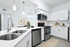 Contemporary kitchen with sleek white cabinetry, stainless steel appliances, and elegant pendant lighting.