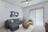 Modern living room with a plush gray sectional sofa, stylish artwork, and natural light from floor-to-ceiling windows, offering a cozy and inviting atmosphere.