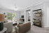 Bright and spacious living room featuring modern furniture, elegant shelving, and access to a lush outdoor view through large sliding doors.