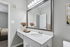 Chic bathroom with large mirror, elegant countertop, and stylish decor adding a touch of luxury.