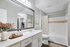 Charming bathroom with sleek countertops, large mirror, elegant lighting, and decorative touches. Featuring a modern bathtub and stylish accents.