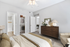 Elegant bedroom with modern decor, featuring a cozy bed, plush seating area, and spacious closet with stylish storage. Natural light enhances the warm, inviting atmosphere.