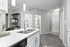 Modern apartment kitchen with elegant white countertops, dual sink, and stylish open shelving, creating a welcoming and spacious entryway.