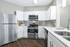 Modern kitchen with sleek stainless steel appliances, elegant white cabinetry, and chic gray tile backsplash.